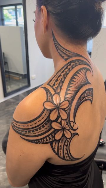 the back of a woman's shoulder with an intricate tattoo design on her upper arm