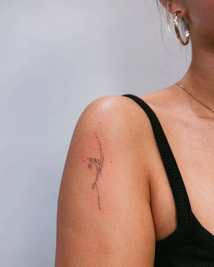 delicate minimalist flower tattoo on shoulder