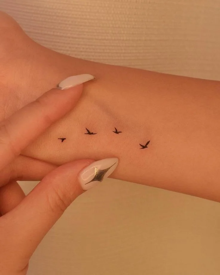 freedom in flight: minimalist bird wrist tattoo