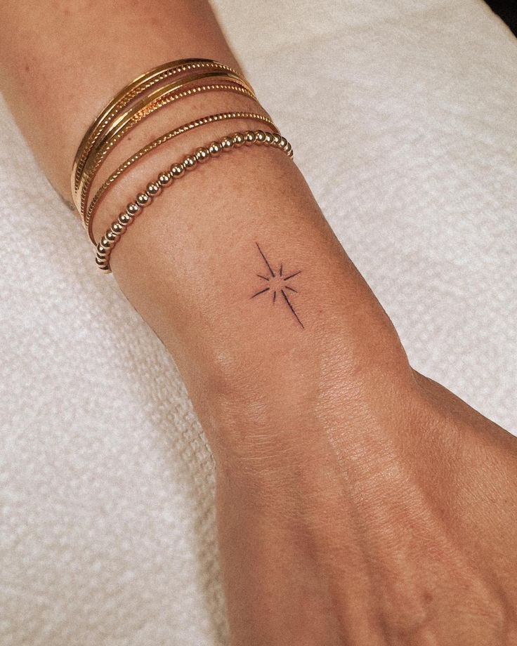 a woman's wrist with a small cross tattoo on the left side of her arm